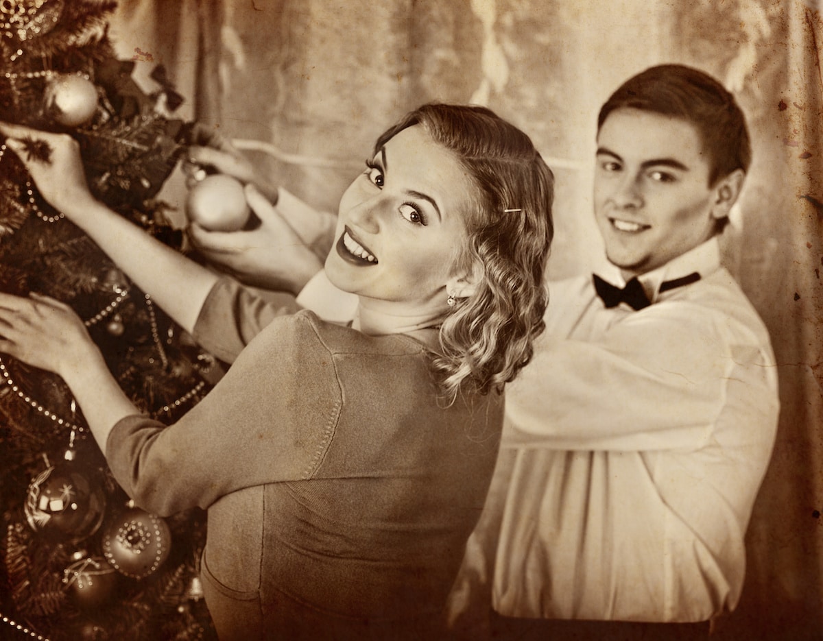 Couple on party decoration Christmas tree. Black and white retro.Old photo on yellow paper.